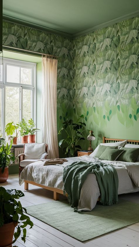 Step into tranquility with our serene green bedroom, where nature-inspired wallpaper creates a calming, forest-like ambiance. The soft, leafy patterns in varying shades of green on the walls are perfectly complemented by a wooden bed frame adorned with crisp, white linens and lush green throw pillows. A cozy armchair by the large window, draped with light, sheer curtains, invites natural daylight to flood the space. Houseplants in terracotta pots enhance the natural vibe, and a light green rug at the foot of the bed adds a touch of comfort. Complete with a wooden nightstand and a vintage lamp, this room is your perfect escape to nature’s tranquility. Earthy Bedroom Wallpaper, Calming Forest, Cozy Armchair, Light Green Rug, Green Bedroom Design, White Linens, Feature Wall Bedroom, Earthy Bedroom, Inspired Wallpaper