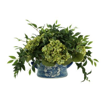 This elegant hydrangea and ruscus arrangement brings a touch of modern sophistication to your home or office. Our beautiful faux green hydrangea is offset by the deep greenery of the ruscus bush - creating a contemporary look that adds a breath of fresh air to any room. It comes complete with a subtle blue and white ceramic vase, adding an additional hint of style! Perfect for intimate dinners or special occasions, this hydrangea and ruscus arrangement will make your living space feel inviting a Green Floral Arrangements Wedding, Hydrangea Potted, Hydrangea Centerpiece, Hydrangea Arrangements, White Ceramic Vase, Faux Hydrangea, Green Hydrangea, Orchid Arrangements, White Ceramic Vases