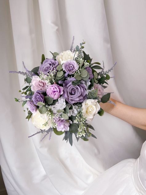 "More beautiful wedding flowers https://bridalstoryus.etsy.com  Lavender bridal wedding bouquet is created with high quality silk flowers. These handmade artificial wedding bouquets make beautiful additions to wedding and event floral arrangements. Flowers: lavender, peonies, roses, eucalyptus and fillers.  Colors: lavender, lilac, white, pale champagne, green. Handle: wrapped in ivory satin ribbon. Size: bridal bouquet is approximately 14\" wide, bridesmaids bouquet is 8\". SUGGESTION: steaming the bouquets, boutonnieres, corsages upon receiving them and you will see how easily they will take the original shape and wrinkles will be removed too. Purchase options:  PRICES ARE FOR THE 1 ITEM ONLY! * Bridal bouquet 14\" * Bridesmaids bouquet 8\" * Boutonniere * Corsage * Boutonniere #1 is wra Lavender And Lilac Bridal Bouquet, Lavender Flowers For Wedding, Flower Bouquet Purple And White, Lilac Flower Bouquet Wedding, Lilac And Eucalyptus Bouquet, Sage Green And Lavender Bouquet, Lavender And Sage Wedding Bouquet, Purple Cascade Bouquet, Lilac Decor Wedding