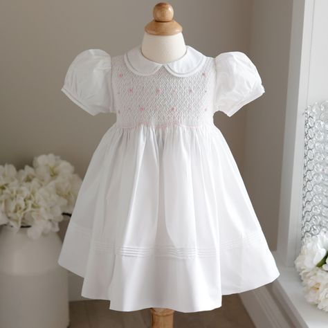 This White Smocked Heirloom Dress By Feltman Brothers Is Super Sweet! The Traditional Style Dress Has A Peter Pan Collar With A Matching Trim That Is Hand-Sewn With Faggoted Stitching (Very High-End Feature). The Short Puffed Sleeves Have A Matching Band That Is Also Hand-Sewn With Faggoted Stitching. The Entire Bodice Is Smocked In A Lattice Design With Pink Embroidery. Sweet Little Pink And White Bullion Roses Are Hand Sewn On Top Of The Lattice Embroidery. The Bottom Of The Smocking Has An Em Lattice Embroidery, Feltman Brothers, Heirloom Dresses, Pink Embroidery, Lattice Design, Matching Band, Puffed Sleeves, Pan Collar, Peter Pan Collar