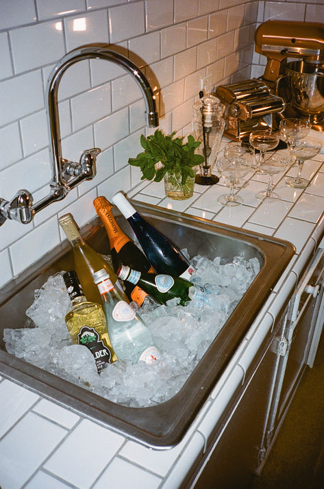 Utilizing my sink is my current favorite way to add a cute bar setup to my evening. Pour in a bunch of ice and add your libations, maybe a few oysters on ice, et voila! My favorite easy hosting tip. Sink Ice Bucket, Ice In Sink For Drinks, Hosting Drinks At Home, Dinner Party Bar Setup, Apartment Cocktail Party, Apartment Hosting Aesthetic, Classy Party Food, Party Bar Set Up, Summer Hosting Ideas