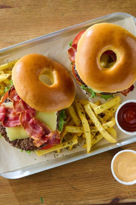 Two brioche bagels filled with burger patties and toppings on a tray with fries and dips. Bagel Burger, Homemade Burger Patties, Bacon Bagel, Seasoned Fries, Homemade Burger, Burger Patties, Burger Night, Bacon Tomato, Homemade Burgers