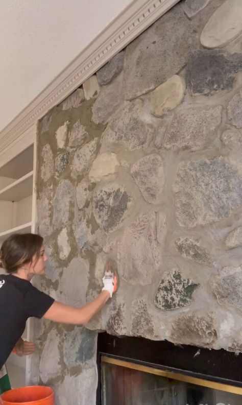 Melissa Tyler applying mortar to her fireplace stones with gloved hands. Stone Fireplace White Grout, How To Overgrout Stone Fireplace, Concrete Over Stone Fireplace, Over Mortar Stone Fireplace, Grouting Stone Fireplace, Painting Faux Rock Fireplace, Over Grouting Stone Fireplace, Make Concrete Look Like Stone, Paint Rock Fireplace Makeover