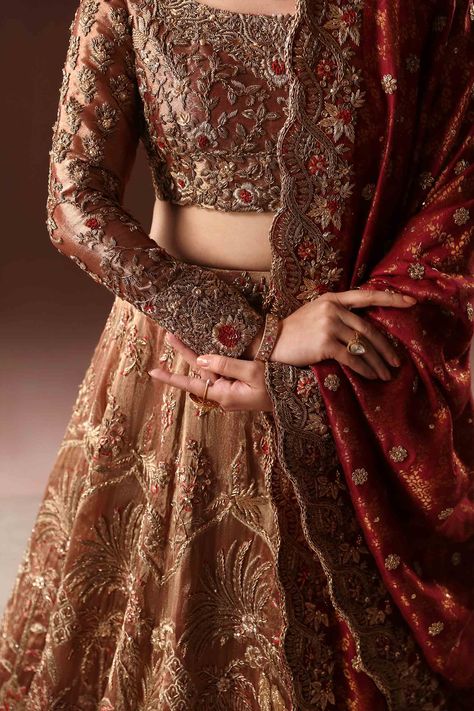 Royal Rusted Gold Embroidered Pakistani Bridal Dress Lehenga choli rafted flora and fauna cover the lehnga with intricate zardozi work with touches of rust resham. Hints of gilded golden 'succha' gota add further beauty to this regal design. Detailed Description: SKU: BB301 Detailing: Embroidery, Motifs, Naqshi, Sequins, Dabka, Zari Color: Rusted Gold Fabric: Jamawar, Tissue, Crimson Chiffon Design: Fully Embellished Dress with Embroidery Event: Bridal wear, Wedding