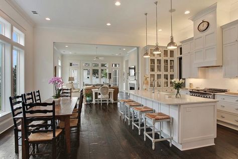 source: Troyer Builders  Chic open kitchen design featuring creamy white cabinets paired with carrera marble countertops and subway tile backsplash. Restoration Hardware Harmon Pendants over long kitchen island with carrara marble top and lined with backless white seagrass bar stools. Eat-in kitchen with farmhouse dining table surrounded by ladder black dining chairs over rustic wide plank wood floors. Kitchen Island And Dining Table, Kitchen Island Stools With Backs, Island And Dining Table, Kitchen Design Layout Island, Kitchen With Island Layout, Rustic Counter Stools, White Kitchen Bar Stools, Carrera Marble Countertops, Kitchen With Long Island