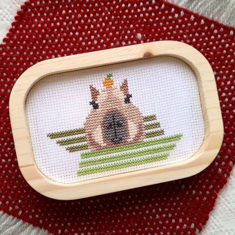 A cross Stitch embroidery of a capybara with an orange on the head, in a lake represented in a geometric rectangles in green Capybara Cross Stitch Pattern, Capybara Embroidery, X Stitch, Stitch Embroidery, Cross Stitching, Counted Cross Stitch, Cross Stitch Embroidery, Embroidery Stitches, Embroidery Patterns