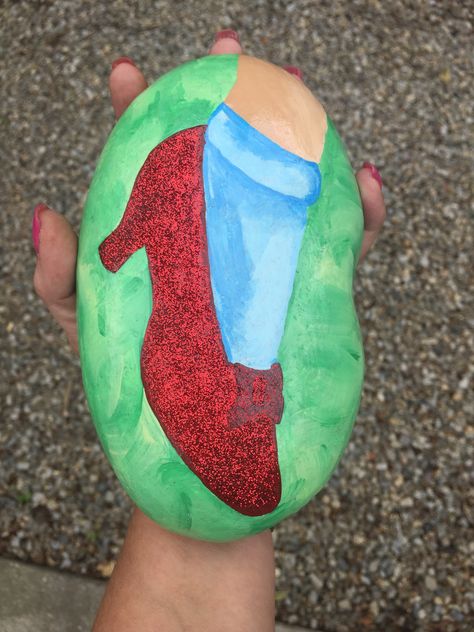 Dr Seuss Painted Rocks, Wizard Of Oz Painting Ideas, Shoe Rock Painting, Wizard Of Oz Art Paintings, Barbie Painted Rocks, Kindness Garden, Wizard Of Oz Painted Rocks, Red Slippers Wizard Of Oz, Diy Mickey Mouse Ears