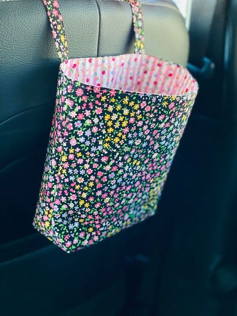 "Looking to add a bit of personality to your ride?  A handcrafted reusable fabric car bag is a decorative way to keep your vehicle clean and clutter free.  Fabric bag holds cell phones, accessories, receipts, snacks, keys, grocery/shopping bags, trash, etc. Also consider hanging in the home or office on doorknob/hook to store most anything.  Makes a wonderful wheelchair bag. Exterior and interior fabric is 100% cotton and interfaced with medium weight interfacing to add extra durability.   Machi Wheelchair Bags, Car Fabric, Car Trash Bag, Sewing To Sell, Cute Sewing Projects, Grocery Shopping Bags, Tote Bags Sewing, Cute Car Accessories, Car Trash