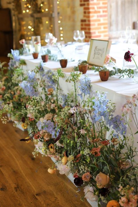 Meadow boxes filled with natural seasonal flowers line the front of a top table at a wedding. Meadow Flower Wedding Table, Top Table Meadow Flowers, Meadow Garden Wedding, Wildflower Top Table, Indoor Wildflower Wedding, Meadow Wedding Table, Meadow Arrangement Wedding, Meadow Boxes Wedding, Meadow Theme Wedding