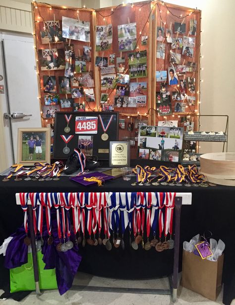 Senior table with awards and pics, track medals, golf trophies. Backdrop is chicken wire panels with butcher paper and string lights, pics are displayed on chicken wire w/ mini clothes pins. Track Medal Display Ideas, Graduation Award Display, Ffa Awards Display, Medal Display Ideas Golf, Senior Volleyball Table Display, Track Graduation Party Ideas, Signing Day Table College Track, Track Themed Graduation Party, Track Medals Senior Pictures