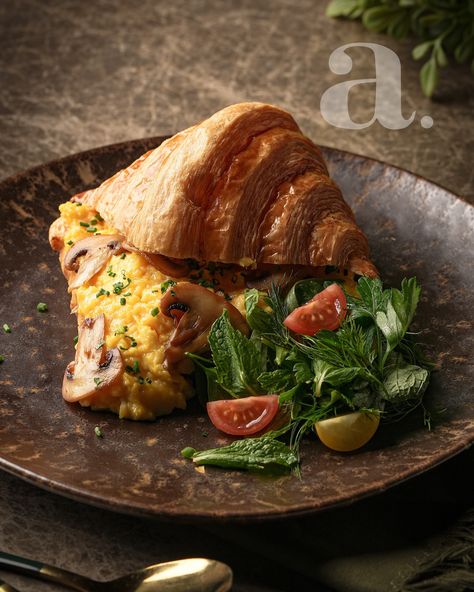 Capture Your Brand’s Essence with Us! Dive into the artistry behind this food photograph—an exquisite display of culinary elegance. The soft, natural lighting gently wraps around the golden, flaky croissant, perfectly complemented by the creamy, rich scrambled eggs studded with sautéed mushrooms. The contrast between the vibrant greens of the fresh salad and the rustic, earthy tones of the textured plate adds depth and visual appeal, drawing the eye effortlessly to the details. The dark, mu... Sautéed Mushrooms, Fresh Salad, Sauteed Mushrooms, Natural Lighting, Fresh Salads, Scrambled Eggs, Soft Natural, Earthy Tones, The Golden