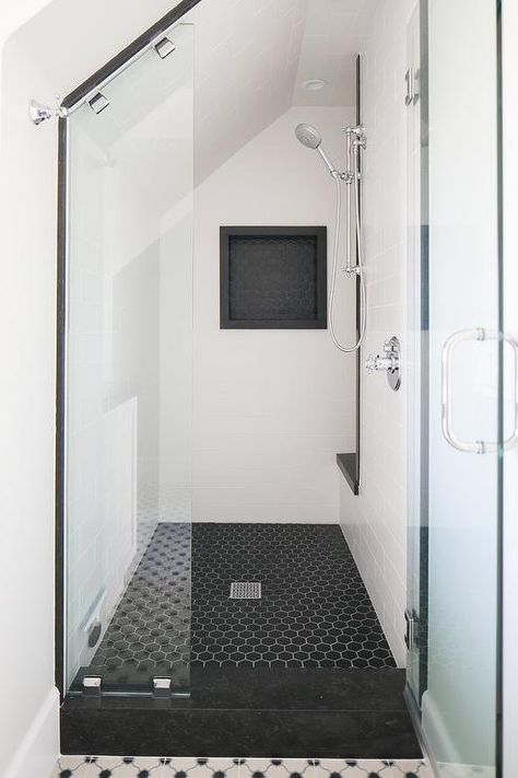 Chic black and white walk in shower boasts black hex floor tiles lined with white stacked wall tiles fitted with a black hex tiled shower niche located on a wall adjacent to an exposed plumbing polished nickel shower kit mounted beside a black shower bench under a sloped ceiling. Black And White Shower Niche, Exposed Plumbing, Tile Shower Niche, Shower Black, Shower Tiles, Small Shower, Bathroom Black, Hexagon Tile, Attic Bathroom