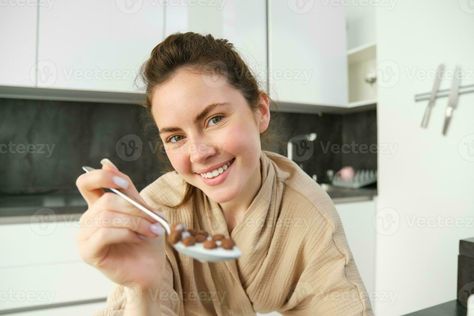 Beautiful smiling woman, holding spoon of cereals with milk, feeding you and looking with love and care, sitting in kitchen, having breakfast in morning Sitting In Kitchen, Spoon Feeding, Learning Art, Smiling Woman, Love And Care, Wedding People, Learn Art, Heart Tree, Cityscape Photos