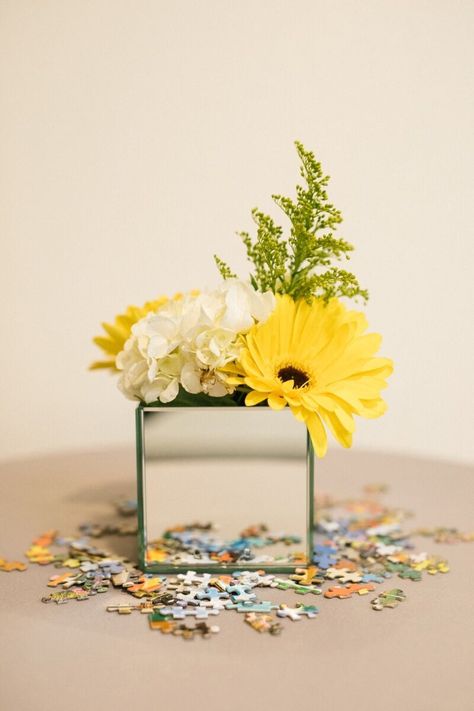 Mirrored Box Centerpiece with Puzzle Pieces Photography By: Jordan Brian Photography #MirroredBox #Flowers #PuzzlePiece #EventDesign #EventDecor #CorporateEvent #Centerpiece #Yellow #Multicolor #Greens #DFWEventDesign Puzzle Theme Centerpiece, Brain Centerpieces, Puzzle Piece Centerpieces, Puzzle Piece Centerpiece Ideas, Puzzle Theme Party, Conference Centerpieces, Byron Wedding, Conference Decor, Puzzle Ideas