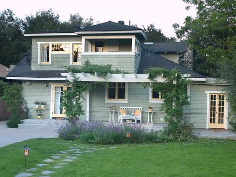 A soft sage body color and sun-yellow accents complement the surrounding landscape, as well as the silvery gray concrete patio and bluestone pathway. By painting the pergola white to match the home's trim, the add-on feels like a natural extension of the architecture. Shown: Scotland Road (body); Oklahoma Wheat (windows and doors); Snow Fall (trim); from Behr. Modern Exterior Paint Colors, Behr Exterior Paint, White Home Exterior, Exterior Paint Color Schemes, Craftsman Houses, Exterior Color Palette, Craftsman Exterior, Paint Color Inspiration, Exterior Paint Color