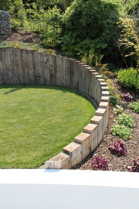 Oak sleepers are used through out the project, set vertically to follow organic curves, retain ground and blend different levels within the garden. Railway Sleepers Retaining Wall, Curved Retaining Wall Garden, Levels Garden Ideas, Railway Sleepers Garden Retaining Walls, Curved Sleeper Wall, Corner Sleeper Planter, Garden Design With Sleepers, Curved Garden Wall Ideas, Sloping Front Garden Ideas