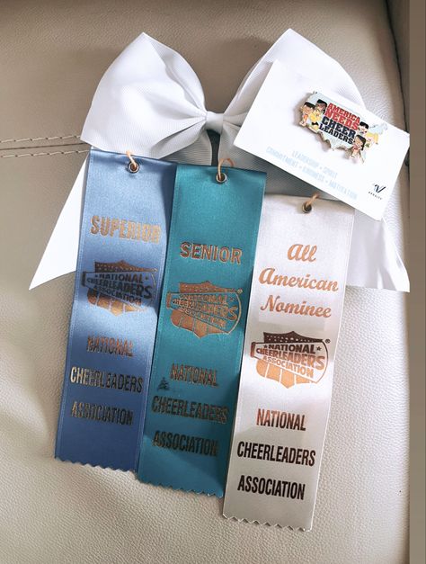 White cheer bow with nca pin it foreword pin, and a blue teal and white nca ribbons Allstar Cheer Aesthetic, Cheer Trophies, Cheer Trophy, Cheer Awards, Nca Cheer, Cheerleading Aesthetic, Cheerleader Aesthetic, Kindness Motivation, Cheer Aesthetic