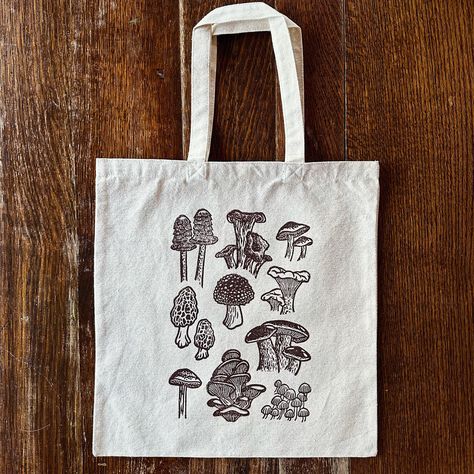 reminder that I recently added these block printed mushroom totes to my shop! I realized that I posted a “coming soon” reel when I made them but never really announced that they’re available 😅 so here they are! | #mushrooms #mushroomart #mushroomdecor #totebag #foraging #blockprinting #printmaking #linocut #printmaker #reliefprinting #blockprint #speedballart #mushies Linocut Tote Bag, Block Print Tote Bag, Sgraffito Ideas, Different Types Of Mushrooms, Printmaking Linocut, Types Of Mushrooms, Nature Motifs, Lino Art, Relief Printing