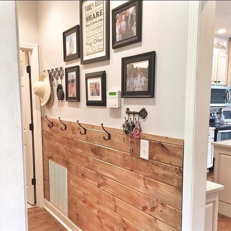 A black-framed gallery wall is positioned over wood shiplap wainscoting in a farmhouse entryway. Use black hooks to store items neatly up off the floor along the walls. Use bright white wall paint to balance out the warm tones of the stained wood panels. Wall Design With Wood, Half Wall Ideas, Accent Wall Entryway, Wood Slab Dining Table, Two Tone Walls, Wooden Accent Wall, Wall Stains, Creative Wall Design, White Wall Paint