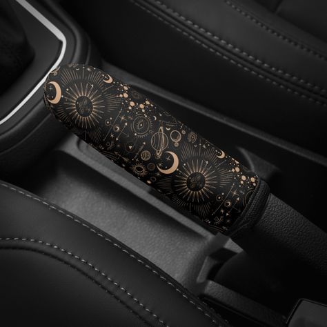 The Celestial Galaxy Car Handbrake Boot Cover is a handmade and custom-designed car decor that brings a unique and witchy touch to any vehicle. Featuring a stunning sun, moon, and stars design in gold and black astrology theme, this boot cover is perfect for women who love celestial-inspired motifs and gothic aesthetics. Crafted with premium-quality materials, the Celestial Galaxy Car Handbrake Boot Cover is both functional and decorative, making it an excellent gift for any occasion. - Handmade and custom designed for a unique touch - Celestial-inspired design with sun, moon, and stars - Gothic and witchy aesthetics in gold and black colors - Functional and decorative car decor - Perfect gift for women who love space and astrology  The Celestial Galaxy Car Handbrake Boot Cover adds a touc Emo Car, Galaxy Car Interior, Witchy Car Accessories, Witchy Car Decor, Moon Car Accessories, Star Steering Wheel Cover, Galaxy Car, Goth Steering Wheel Cover, Cool Car Accessories