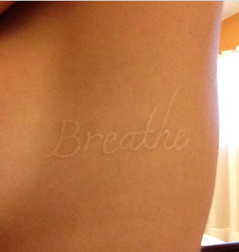 White ink tattoo, love the font. This one word has so much meaning to me on so many levels. I just love looking at it White Word Tattoos, Back Tattoo White Ink, White Tattoos On Tan Skin, White Script Tattoo, White Ink Tattoo Tan Skin, White Ink Tattoo On Dark Skin, White Tattoo On Dark Skin, Healed White Ink Tattoo, Small White Tattoos