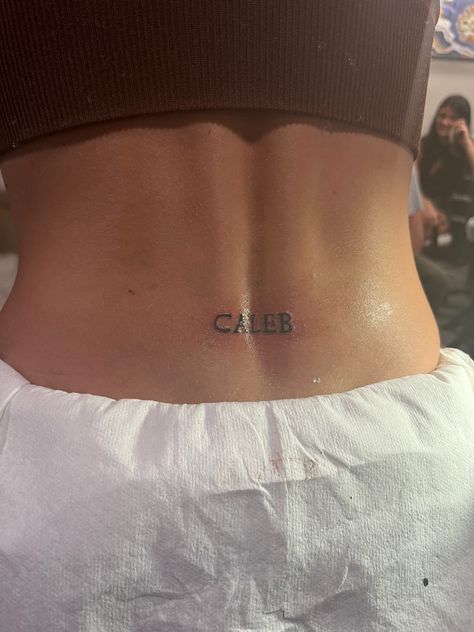 Girly Word Tattoos, Back Mini Tattoo, Letter Tramp Stamp, Cute Dainty Tramp Stamp, Trampstamp Tattoo Words, Lower Back Name Tattoos, Spine Tattoo With Tramp Stamp, Spine And Tramp Stamp Tattoo, Lucky You Tramp Stamp