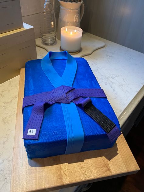 A perfect textured Gi for a great Brazilian Jiu Jitsu purple belt competitor! Chocolate cake with vanilla buttercream dyed blue! Lapel and belt made out of fondant. Jiu Jitsu Cake Ideas, Jujitsu Cake Ideas, Jujitsu Birthday Party Ideas, Jiu Jitsu Party Ideas, Judo Cake Ideas, Jiu Jitsu Birthday Party Ideas, Jiu Jitsu Party, Jiu Jitsu Cake, Judo Cake