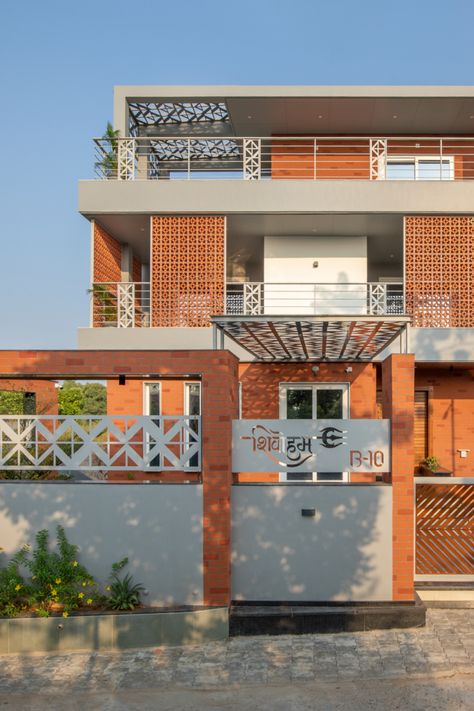 Right at the entrance, the Laser cut Metal shade creating polymorphic patterns as per the light throughout the day rests on expose brick textured columns. The first floor with patterned clay tile screens is sandwiched in between the exposed brick textured two floors reducing the visual mass of the residence. Terracotta Jaali House Elevation, Modern Brick Facade Design, Porotherm Brick House Elevation, Terracota Jali Elevation, Brick Elevation Design, First Floor House Design, Brick Home Exteriors, Terracotta Jali, Brick Elevation