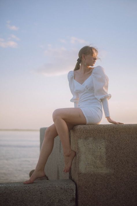 Woman in Dress Sitting on Rock against Blue Sky · Free Stock Photo Dress Poses Sitting, Sitting On Wall Pose, Woman Sitting Reference, Lady Sitting Pose, Elegant Sitting Pose, Beach Model Photoshoot Poses, Women Sitting Poses, Woman Sitting Pose Reference, Female Sitting Pose Reference