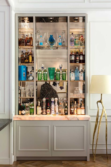 Painted gray bar display millwork with a mirror back and backlit onyx countertop.