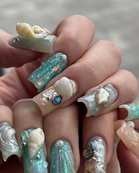 Explore the depths of the ocean with these captivating coffin nails inspired by the sea. With a serene color scheme of aquamarine and delicate pearl white, each nail is meticulously embellished with miniature seashells and starfish, complemented by shimmering pearls that glimmer in the light. The combination of glossy and matte textures creates a striking juxtaposition, evoking the dynamic nature of the ocean's surface.