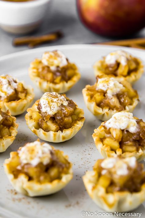 45 degree angle shot of Easy Apple Pie Bites topped with whipped cream and salted caramel sauce on a gray plate with cinnamon sticks, an apple and ramekin of caramel sauce blurred in the background. Bourbon Whipped Cream Recipe, Apple Pie Bites Recipe, Bourbon Apple Pie, Phyllo Cups, Alcoholic Desserts, Apple Pie Bites, Apple Bite, Best Apple Pie, Recipes With Whipping Cream