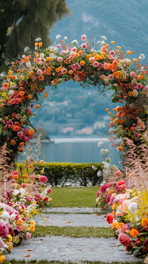 A colorful flower arch, perfect for your wedding day. This stunning display will add a touch of elegance and romance to your ceremony. The vibrant hues of the flowers will create a beautiful backdrop for your special day. Colorful Garden Wedding Ideas, Multicolor Flower Wedding, Multicolored Flowers Wedding, Wedding Wedding Theme, Bridal Vision Boards, Wedding Arch Colourful, Wedding Arch Ideas Colorful, Sunset Color Theme Wedding, Wedding Aisle With Flowers