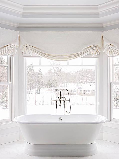 A bank of bay windows offers the perfect spot to nestle a freestanding tub. With the shades left open, natural light floods the entire room and gives bathers soothing views of the landscape beyond./ Blinds For Bathroom Windows, Roman Shades Bathroom, Roman Bathroom, Window Valence, Bay Window Treatments, Bathroom Window Curtains, Bathroom Window Treatments, Bathroom Blinds, Bathroom Window