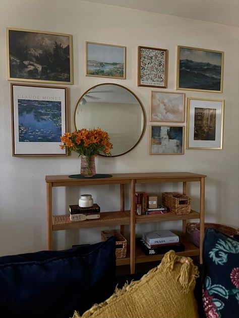 Entryway gallery wall including impressionist art prints and a gold mirror. A light wood console bookcase and lightly styled shelves with a few classic books, fashion books, and candles. Gallery Wall Console Table, Wall With Console Table, Gallery Wall Above Console Table, Gallery Wall With Mirror, Entry Way Gallery Wall, Large Circle Mirror, Entryway Gallery Wall, Art Over Bed, Home Sense