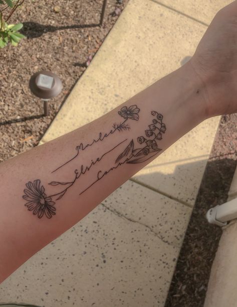 This tattoo was created for my 3 kiddos! Each child’s name goes with each of their birth month flowers. Cosmos for October, daisy for April, and lily of the valley for May. Tattoo Lily Of The Valley, Tattoo Lily, Tato Nama, Name Flower Tattoo, Lily Of The Valley Tattoo, Tato Lengan Bawah, Cosmos Tattoo, Daisy Tattoo Designs, Valley Tattoo