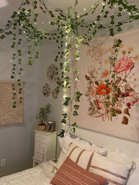 fairy garden themed bedroom with hanging vines, fairy lights, and floral decor Vines In Bedroom Slanted Ceiling, Bedroom Inspirations Vines, Pink Room With Vines, Vines In Shower Decor, Vines On Slanted Ceiling, Vine Ceiling Bedroom, Vines On Roof Bedroom, Ivy Vines Bedroom, Vines In Bedroom Ceiling