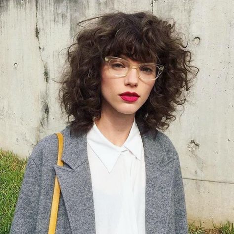 Audrey Watson on Instagram: “Talk about a major babe! Look at this amazing hair! Who wants this haircut?! . . . . . #hairinspiration #curlyshag #curlybangs #casualcool…” Bottleneck Bangs Curly Hair, Queer Curly Haircut Long, Natural Red Lipstick, Curly Bixie Shag, 80s Curly Bangs, Bixie Haircut Girl Curly, Bangs And Glasses, Curly Bangs, Curly Hair With Bangs