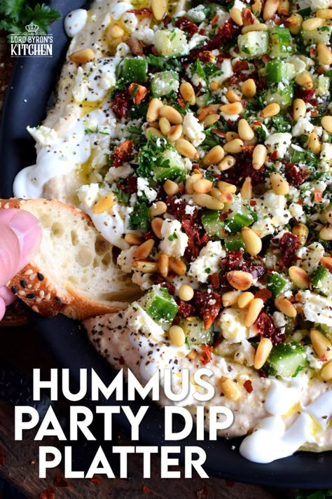 What's a party without dip? Hummus Party Dip Platter is a large, layered dip that's just perfect for entertaining a crowd. This all-in-one dip has hummus, sour cream, pine nuts, sun dried tomatoes, cucumbers, feta, and a few other ingredients too! Serve this on any occasion for a delicious, crowd-pleasing appetizer! #hummus #dip #appetizer #party #platter #spread 7 Layer Mediterranean Dip With Hummus, Hummus With Toppings, 7 Layer Greek Hummus Dip, Dipping Board Ideas, Hummus And Tzatziki Dip, Loaded Hummus Recipe, Hummus Platter Ideas Parties, Pita Hummus Platter, Hummus Dip Platter