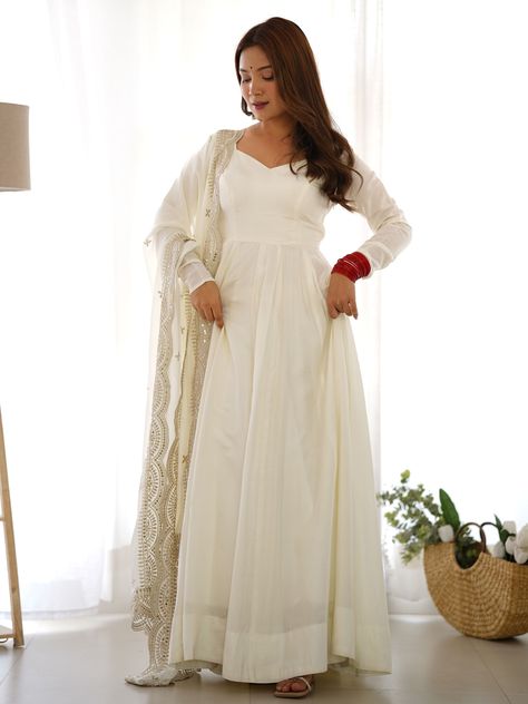 Our stunning off-white color silk anarkali suit, is a timeless piece that embodies elegance and grace. This exquisite ensemble features a luxurious silk anarkali suit paired with a matching silk pant, creating a harmonious blend of traditional and contemporary fashion. The highlight of this outfit is the georgette dupatta, beautifully adorned with intricate embroidered work, sequin embellishments, and a delicate cutwork border. The entire set is designed to offer a perfect balance of comfort and White Anarkali Suits, Engagement Gown, White Anarkali, Silk Anarkali Suits, Lehenga Crop Top, Lehenga Choli Wedding, Reception Gown, Party Wear Lehenga Choli, Bollywood Lehenga