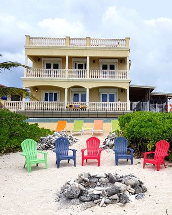 air bnb wedding venue beach with multi-colored chairs and stone fire pit Airbnb Wedding Venues, Amazing Airbnb, Colored Chairs, Best Airbnb, Airbnb Wedding, Stone Fire Pit, Wedding Venues Beach, Air Bnb, Air B And B