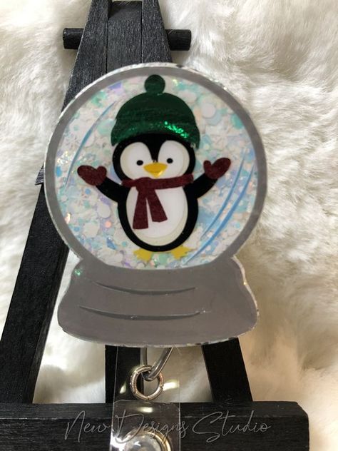 Super cute with just a touch of sparkles, this little penguin loves playing in the Snow. This is a very pretty iridescent white/blue glitter with snowflakes. This is a 2-inch badge reel. Great gift for someone special that you want to show a little appreciation for or just add a touch of the holidays to your work environment. Each design is cut vinyl and layered on then topped with at least 2 coats of epoxy resin making them durable, easy to clean and super shiny! Penguin Snow Globe, Resin Making, Medical Badge, Penguin Love, Playing In The Snow, Iridescent White, Id Badge Reels, Belt Style, Snap Clips