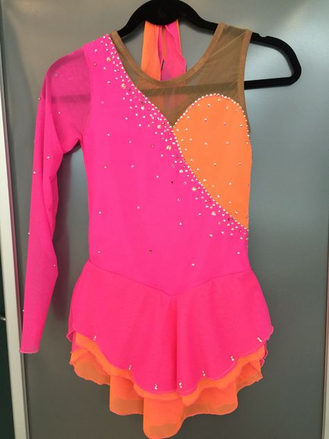 Neon pink and orange figure skating dress with various size size crystals. One sleeve asymmetric by Suzanne skate dresses on face book or sk8dress.com Orange Figure Skating Dress, Purple Figure Skating Costume, Purple Figure Skating Dress, Ice Skating Dresses Pink & Orange, Pink Dance Costumes, Rainbow Figure Skating Dress, Roller Skating Dress, Twirling Costumes, Figure Skating Competition Dresses