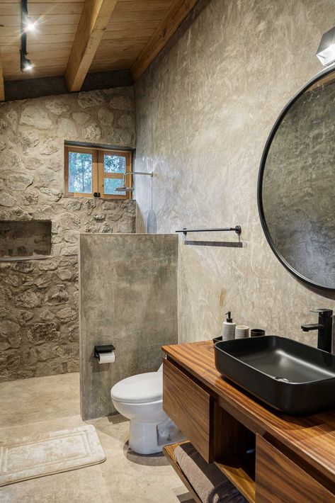 This Modern House Was Made From Locally Sourced Stone Minimalist Stone Bathroom, Shower Natural Stone, Stone Bathroom Ideas Rocks, Rustic Outdoor Bathroom, Modern Spa Bathroom Stone, Stone Wood Glass House, Organic Bathroom, Stone Tile Bathroom, Eclectic Bathroom Design