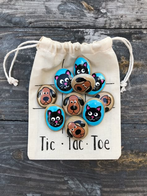 This Cats and Dogs Tic Tac Toe set makes a great gift or stocking stuffer!  There are 5 cats and 5 dogs.  Each smooth stone is carefully hand-painted with acrylics and sealed with a glossy weather-resistant varnish.  Includes a muslin drawstring bag with the Tic Tac Toe grid! Can also be used for matching and sorting! The stones measure about 1 inch each (size and shape will vary). You won't find a better quality of painted stones elsewhere! Find more Tic-Tac-Toe sets here  https://www.etsy.com/ Painted Rock Tic Tac Toe, Tic Tac Toe Rocks, Tic Tac Toe Board, 5 Cats, Floral Wrapping Paper, Tic Tac Toe Game, Craft Show Ideas, Rock Painting Art, Cat And Dog