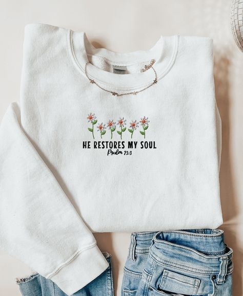 Flower Embroidered He Restores My Soul Christian Crewneck | Psalm 23:3 Bible Verse Christian Sweatshirt | Baptism Gift Idea  💕Be Inspired and wear your faith boldly 🤩 💕PRINTING  Embroidery provides a textured, raised look with durable stitching. With embroidery, garments get a premium and high-end feel due to the textured design. Additionally, it provides durability that does not fade over time.  💕QUALITY : Ideal for any situation, a unisex heavy blend crewneck sweatshirt is pure comfort. Th Cute Sweatshirts Christian, Christian Merch Ideas, Cute Christian Sweatshirts, Christian Embroidery Designs, Christian Boutique, Psalm 23 3, He Restores My Soul, Christian Embroidery, Christian Crewneck