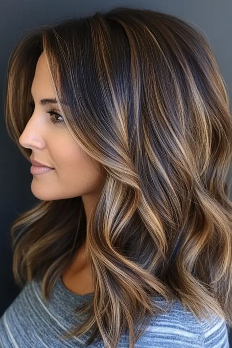 Woman with shoulder-length, wavy hair featuring caramel highlights. Smudge Root Highlights, Medium Length Dimensional Brunette, Caramel Beige Highlights, Brunette Hair Color Inspiration, Brunette Hair Dimension Highlights, Brown With Minimal Highlights, Trendy Brown Hair With Highlights, Highlights On Brown Hair Medium Length, Short Highlights Hair