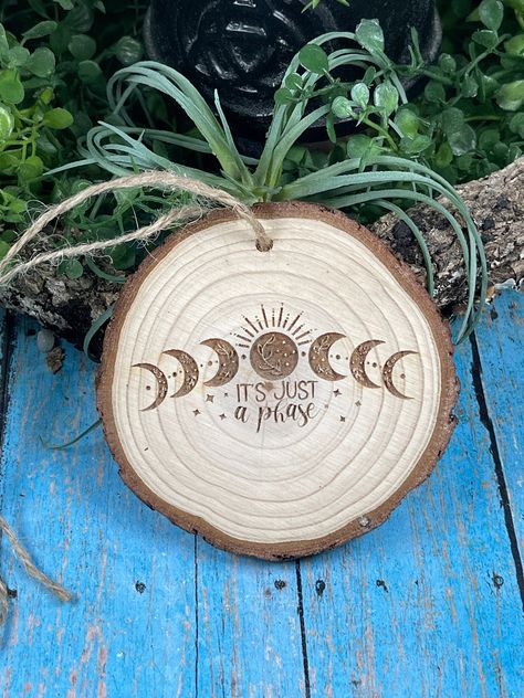 "Laser burned woodslice ornament that reads \"It's Just a Phase\" and features the different moon phases. These ornaments are approximately 3 - 3.5\"and has a jute cord attached for hanging. These woodslice ornaments can be used as Christmas ornaments, hang your favorite one from you rearview mirror in your car, hang them from your kitchen cabinet knobs, or you can choose to just display them or hang on or over your altar. They also make great gifts year round! FREE SHIPPING ON ORDERS OVER $35 Check out our other Etsy shop: \"Hippie Chic Cottage\" for handmade earrings and other creations." Wood Burned Moon Phases, Wood Burning Crafts Diy, Wood Burning Patterns Free, Celestial Crafts, Simple Wood Burning Patterns, Wood Burning Ornaments, Tree Slice Art, Moon Phase Art, Wood Burned Gifts