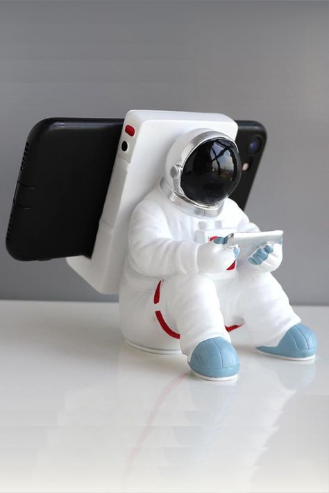 The Creative Astronaut Phone Holder is a unique and fun accessory that securely holds your phone in place. The holder is made of high-quality materials and can be easily attached to any flat surface, making it perfect for hands-free use while watching videos, making video calls, or just adding a cool touch to your desk or nightstand. Store Concept, Tanah Liat, Cell Phone Stand, Cellular Phone, Support Telephone, Tablet Phone, 3d Printers, Cell Phone Holder, Cool Inventions