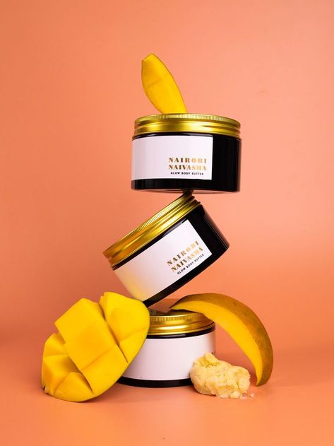 Three Nairobi Naivasha Glow Body Butter jars stacked on top of each other angled and levitating. Product photography styling is completed with raw mango pieces and raw shea butter. The whole composition is in orange and yellow colours. Body Cream Photography, Skincare Product Photography, Product Photography Styling, Soap Photography, Levitation Photography, Mango Cream, Body Butters Recipe, Candles Photography, Food Photography Inspiration